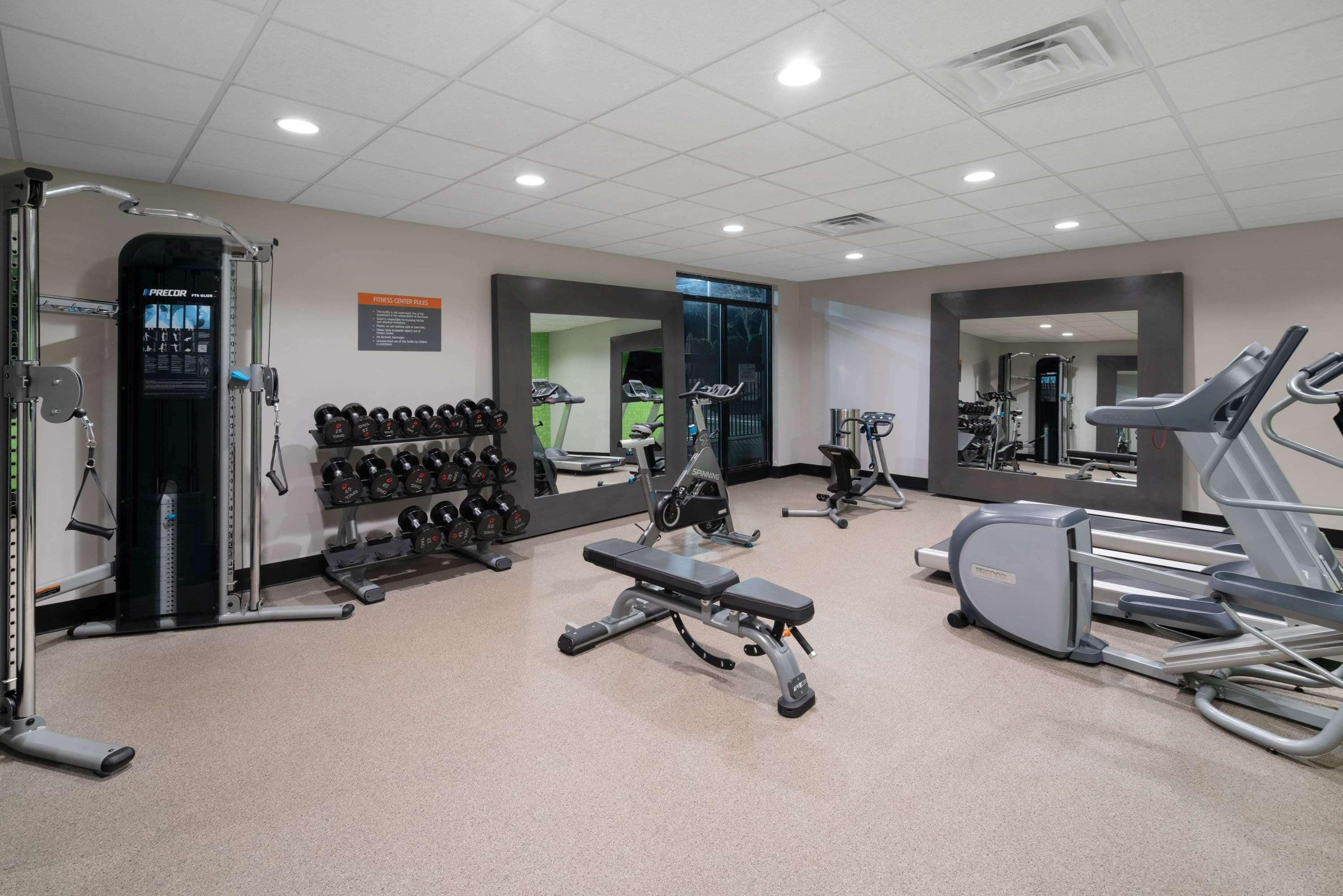 A gym with cardio equipment, weight machines, and dumbbells.