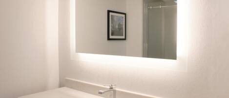 A bathroom with a white sink, a mirror, and a framed picture on the wall.