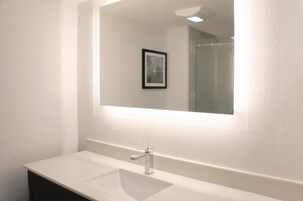 Un baño con un lavamanos blanco, un espejo y un cuadro en la pared.