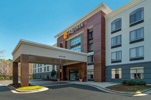 A modern hotel with a prominent 'La Quinta' sign, covered parking, and a landscaped entrance area.
