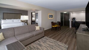 A hotel room with a bed, a sofa, a dining table with chairs, a kitchen area, and a TV. - La Quinta Inn & Suites by Wyndham Raleigh Downtown North (Raleigh)