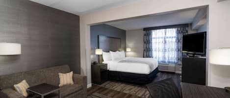 A hotel room with a bed, a sofa, a TV, and a desk.