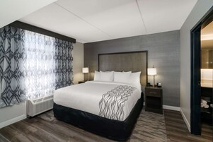 Una habitación de hotel moderna con una cama grande, dos mesitas de noche con lámparas, un calefactor empotrado y un armario con espejo.