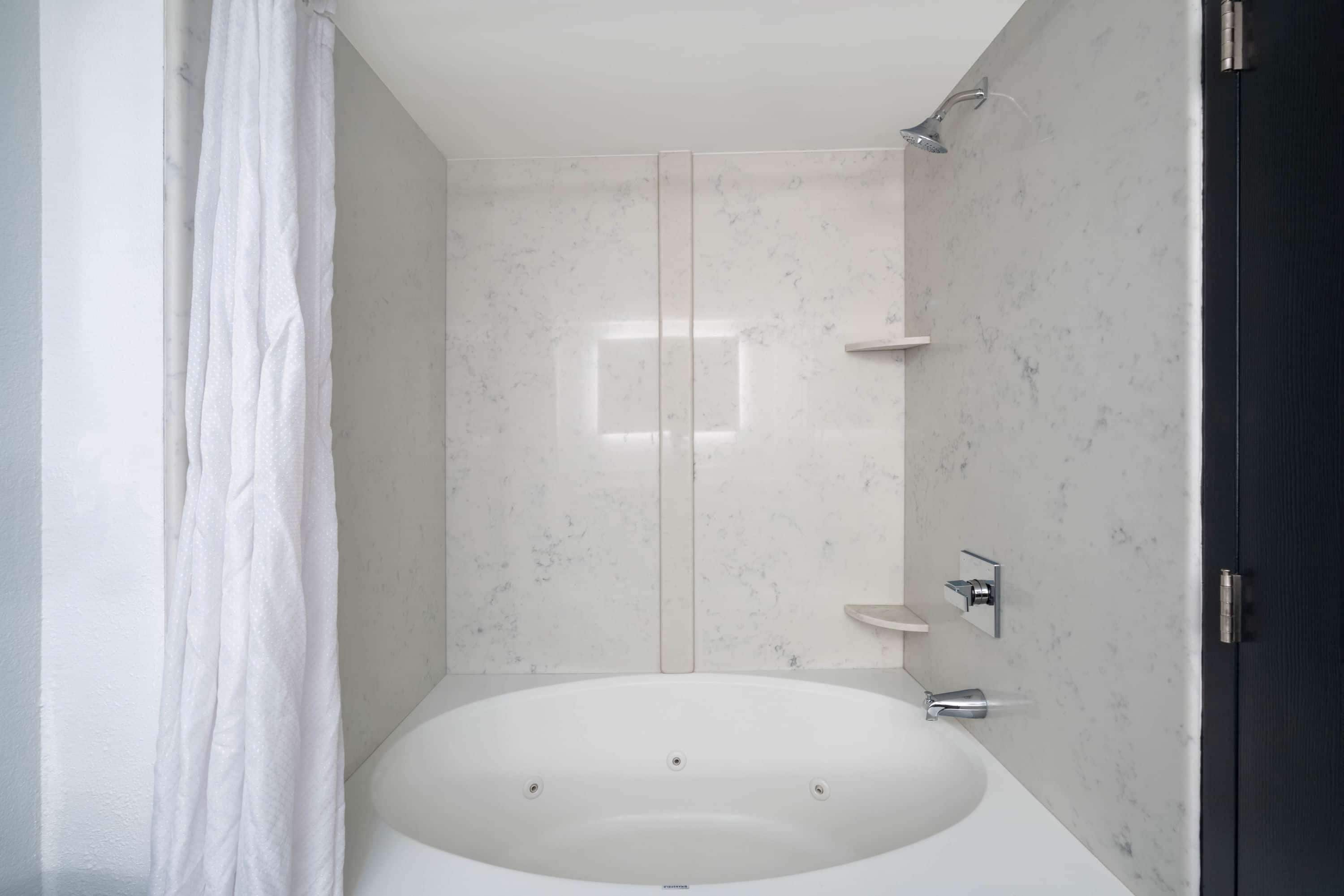A modern bathroom with a freestanding bathtub, a showerhead, and a toilet.