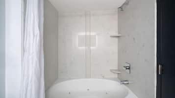 A modern bathroom with a freestanding bathtub, a showerhead, and a toilet.