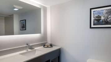 A modern bathroom with a large mirror, a sink, and a toilet.