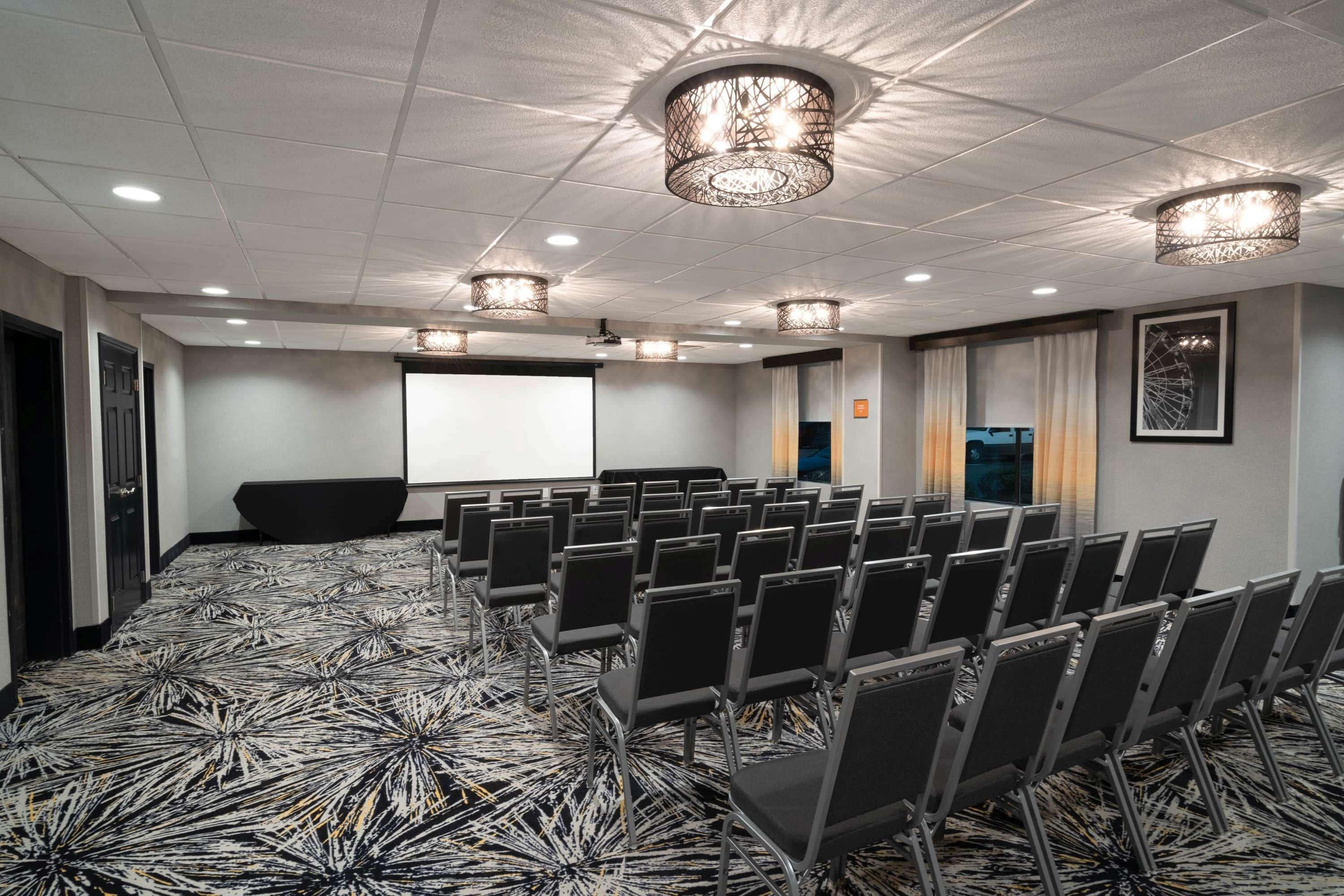 A conference room with rows of chairs, a projector screen, and a large screen.