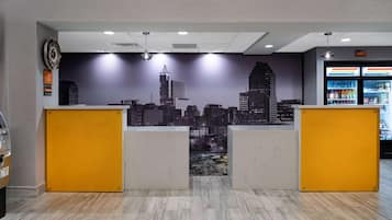 Zona reception con un murale che raffigura la città, un banco e un frigorifero fornito di bevande.