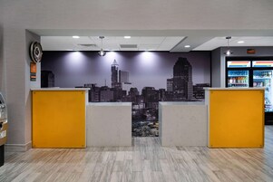 Zona reception con un murale che raffigura la città, un banco e un frigorifero fornito di bevande.