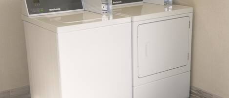 A front view of a modern, white, stacked washer and dryer unit with a control panel on top.