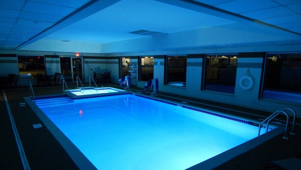 A large indoor swimming pool with clear blue water, surrounded by windows and a tiled floor. - Wingate by Wyndham - Joliet (Joliet)