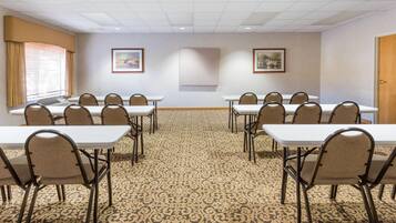 A conference room with a patterned carpet, white tables, and chairs.