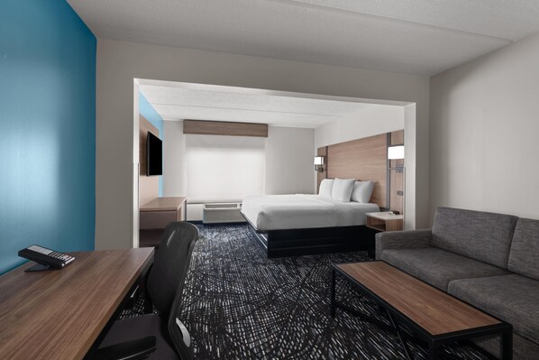 A hotel room with a bed, a desk, a sofa, and a TV.