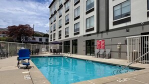 Une piscine avec des chaises longues, un bâtiment doté de nombreuses fenêtres et un panneau sur le mur.