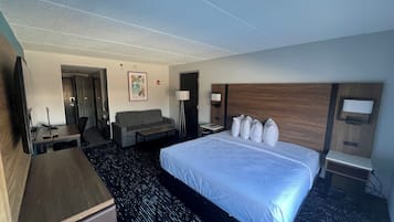 Una habitación de hotel con una cama grande, un sofá, un escritorio y un televisor.