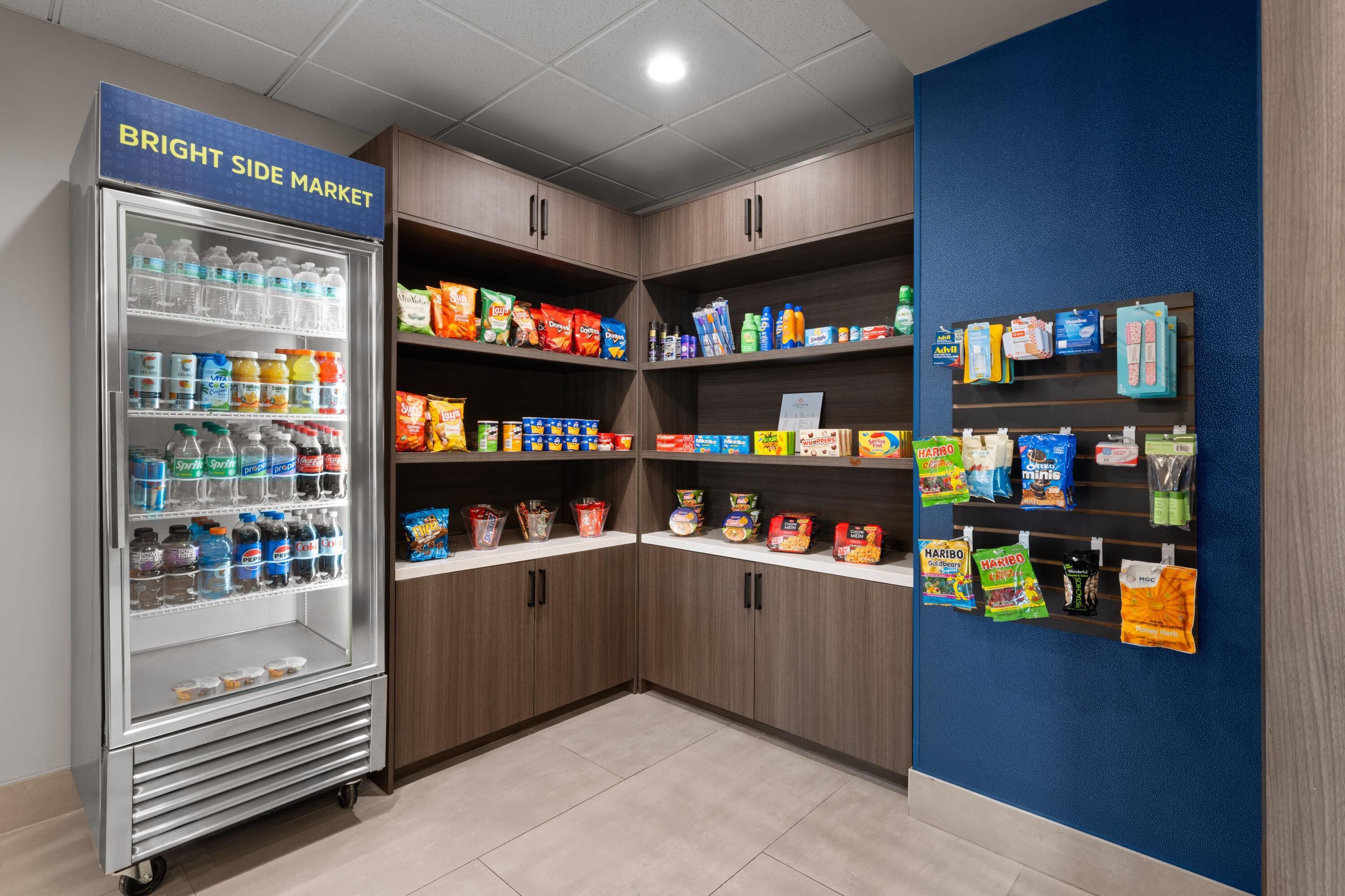 A self-service beverage refrigerator and snack shelves in a store.