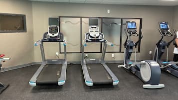 Un gimnasio con cintas de correr, elípticas y una bicicleta estática.