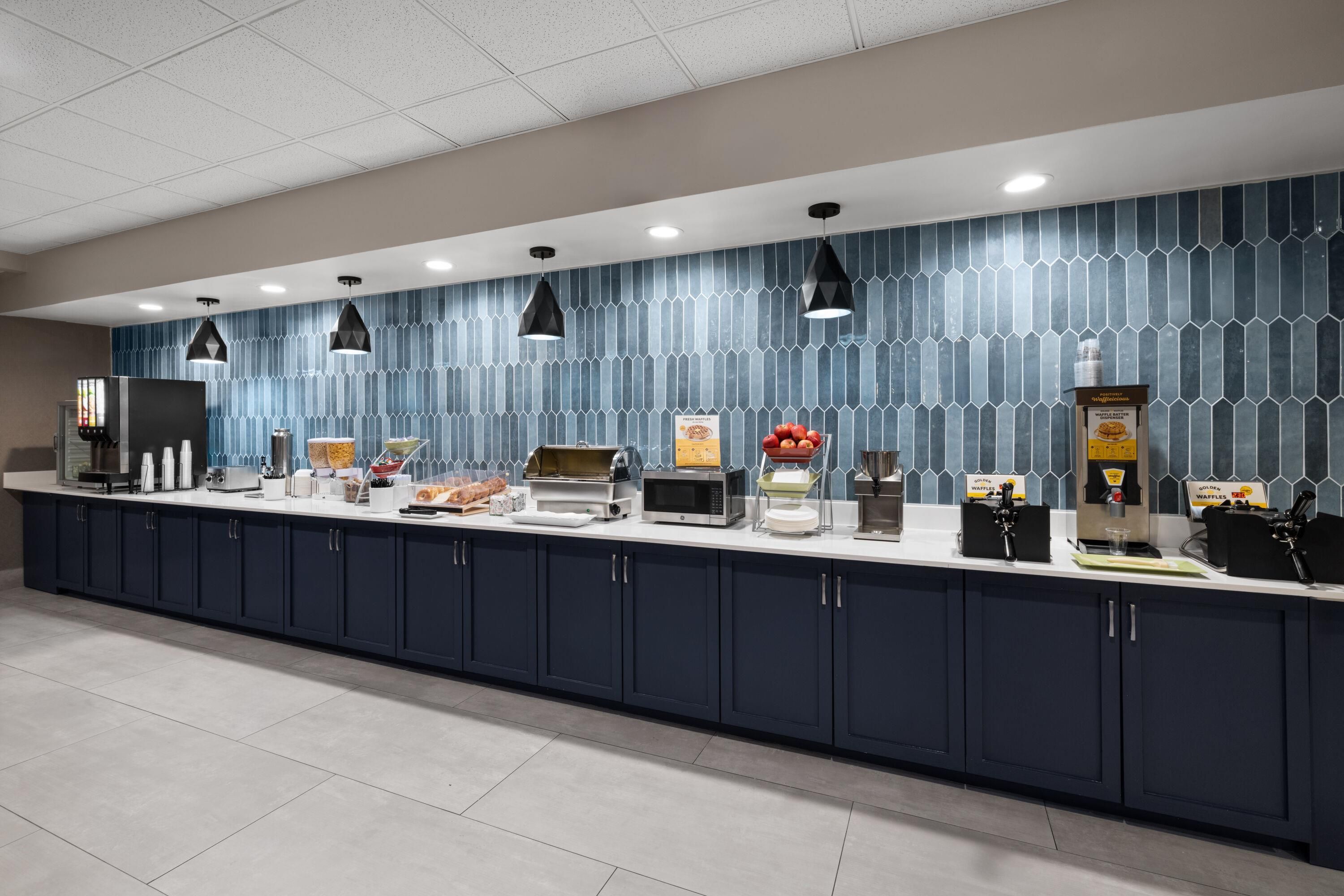 Una barra de desayuno moderna con una barra larga, iluminación colgante y un revestimiento de pared con diseño.
