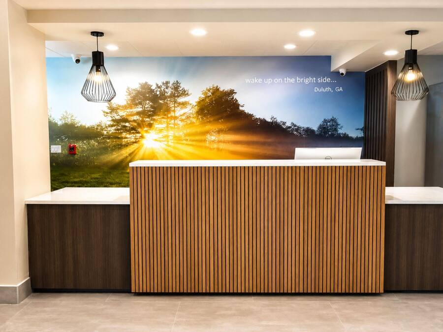 A reception desk with a wooden panel design, a wall mural with a sunrise scene, and pendant lighting.