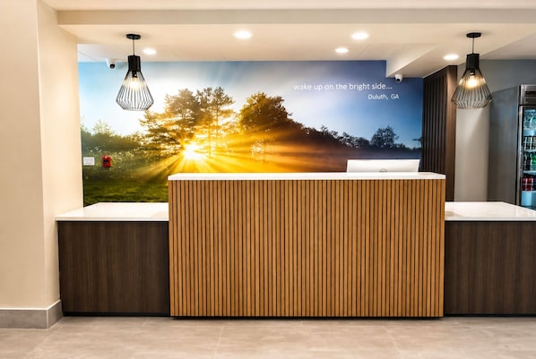 Ein Empfangsschalter mit Holzpaneelen, eine Wandmalerei mit Sonnenaufgangsmotiv und Pendelleuchten.