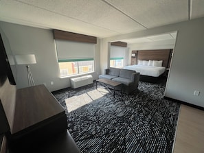 A hotel room with a large bed, a sofa, a desk, and a window with a view of buildings outside. - La Quinta Inn & Suites by Wyndham Duluth/Atlanta (Duluth)
