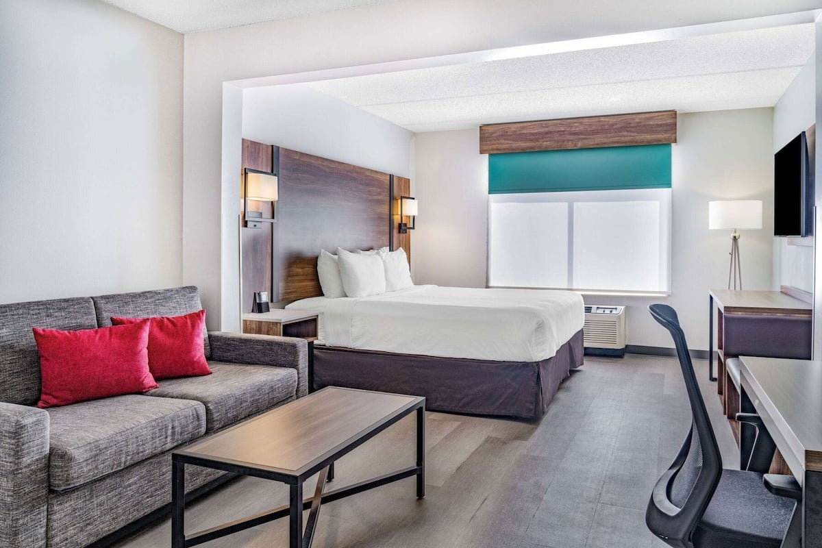 Une chambre d’hôtel avec un lit, un canapé, un bureau et une télévision.