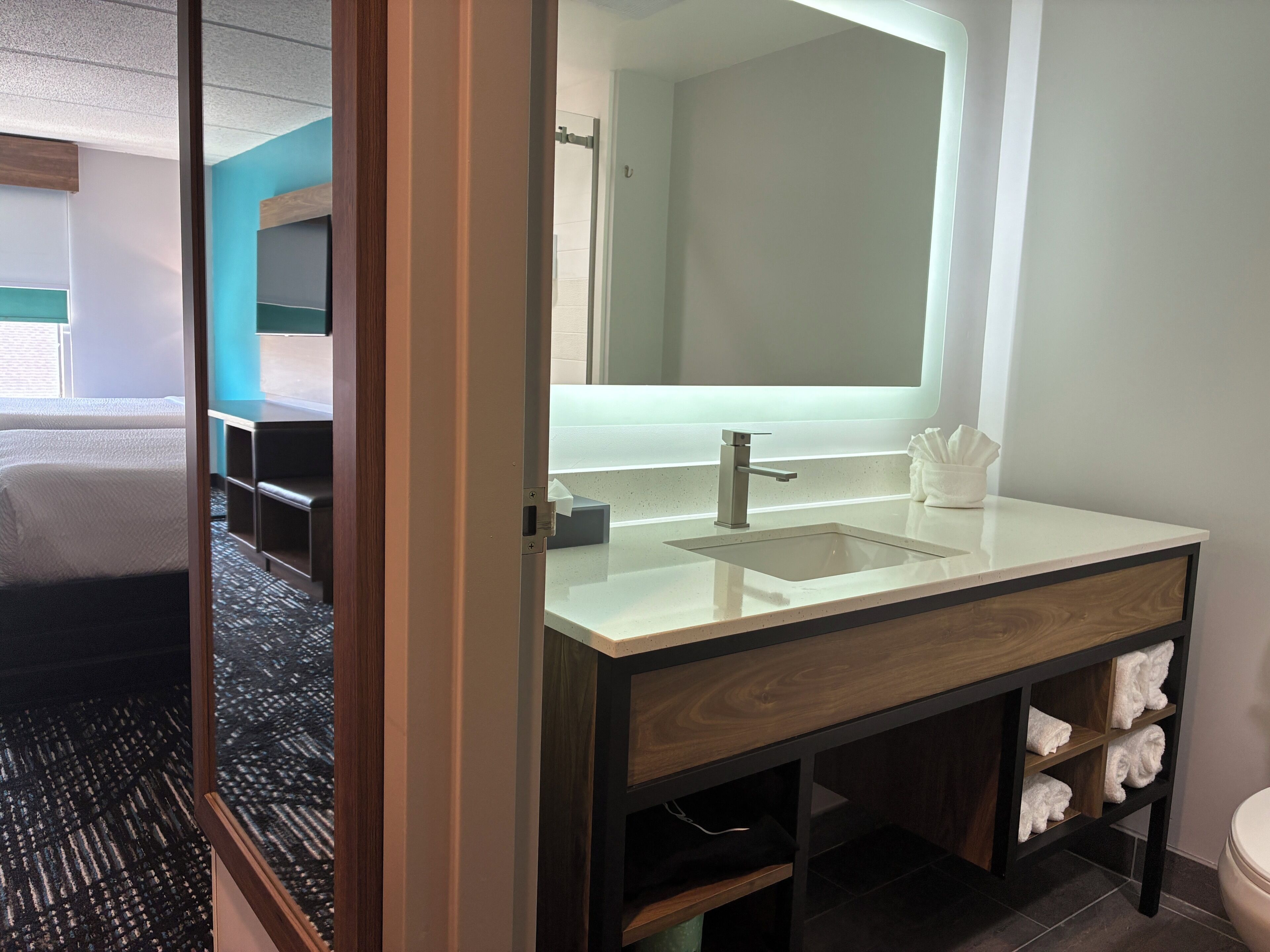 A modern bathroom with a large mirror, a sink, and a toilet.