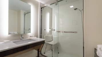 A modern bathroom with a glass-enclosed shower, a vanity with a sink, and a mirror.