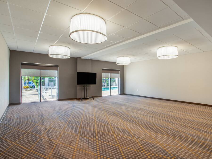 A spacious room with a patterned carpet, large windows, and three ceiling lights.