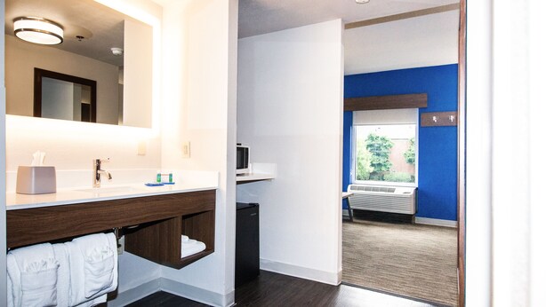 A modern bathroom with a wooden vanity, a mirror, a sink, and a small refrigerator. - Holiday Inn Express & Suites Nashville - Brentwood I-65 by IHG (Brentwood)