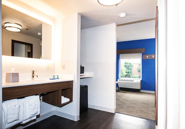 Une salle de bain moderne avec un meuble-lavabo en bois, un miroir, un évier et un petit réfrigérateur.