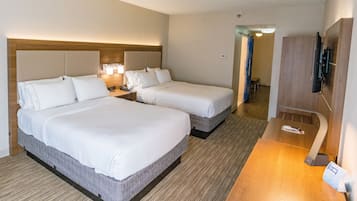 A hotel room with two beds, a desk, a TV, and a bathroom visible in the background.