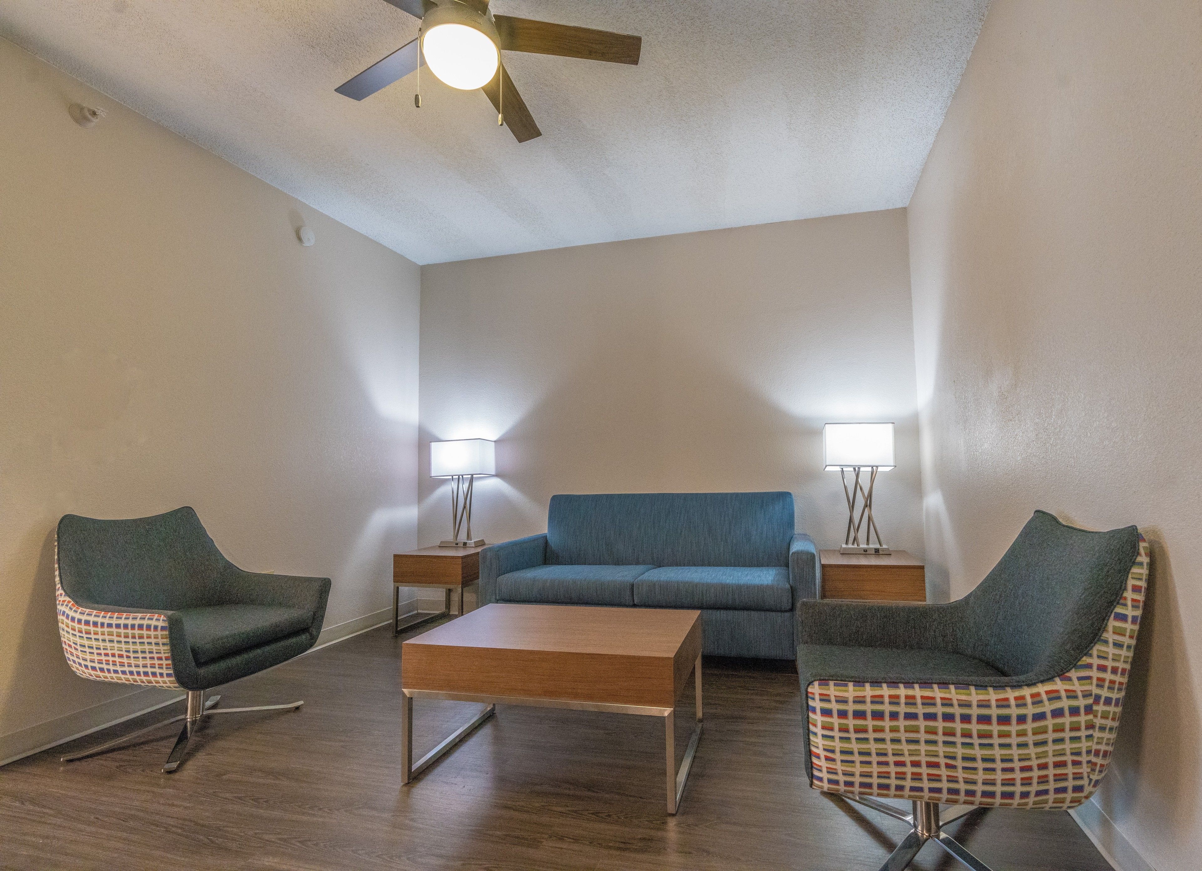 A living room with a blue sofa, two armchairs, a coffee table, and two floor lamps.