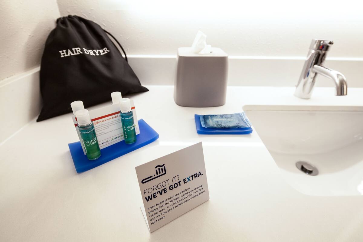 A bathroom sink with a hair dryer, a tissue box, and toiletries on a blue tray.