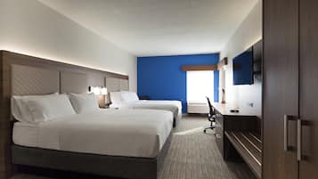 A hotel room with two beds, a desk, a flat-screen TV, and a window.