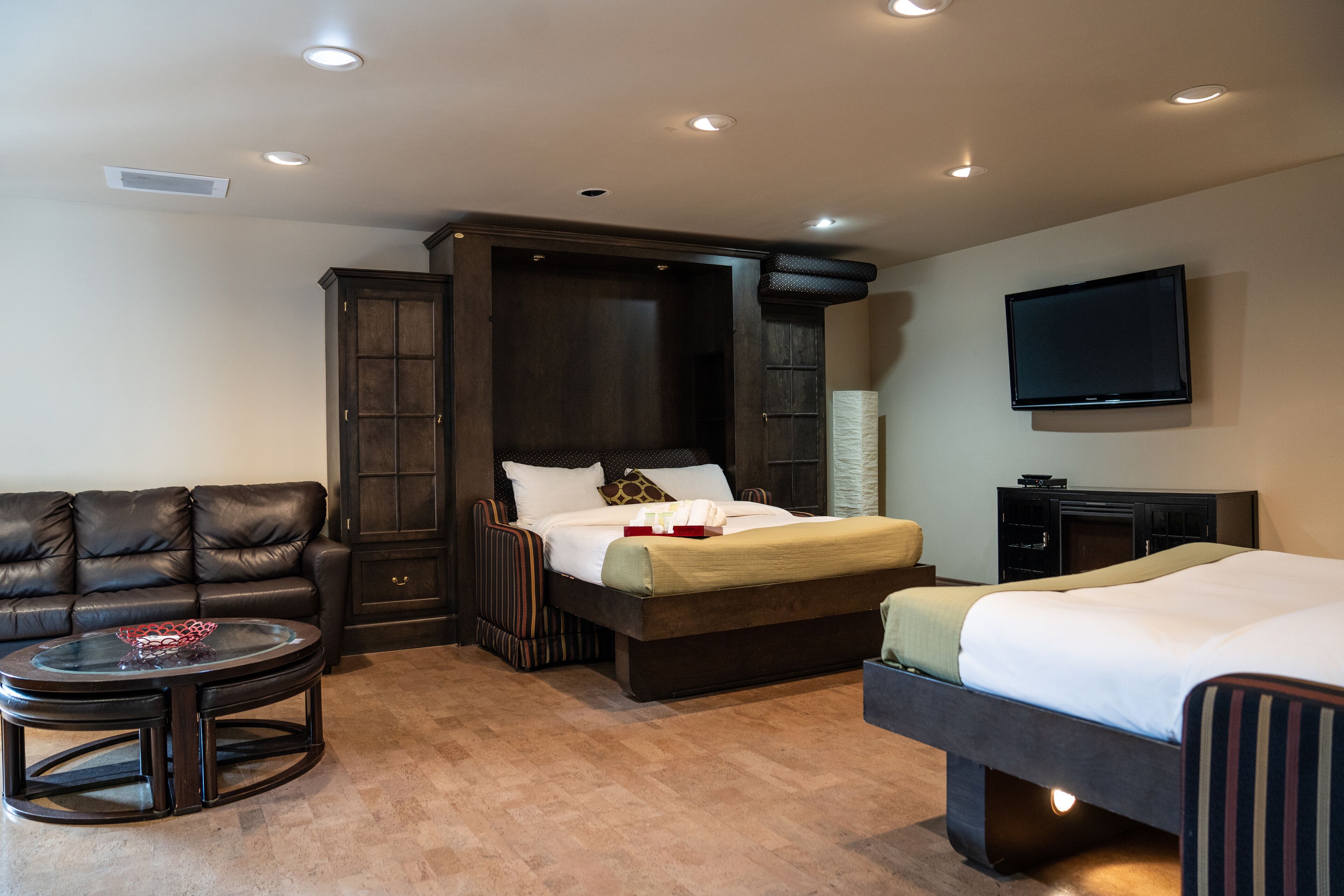 Una camera d'albergo con un letto grande, un divano, una TV e un tavolino.
