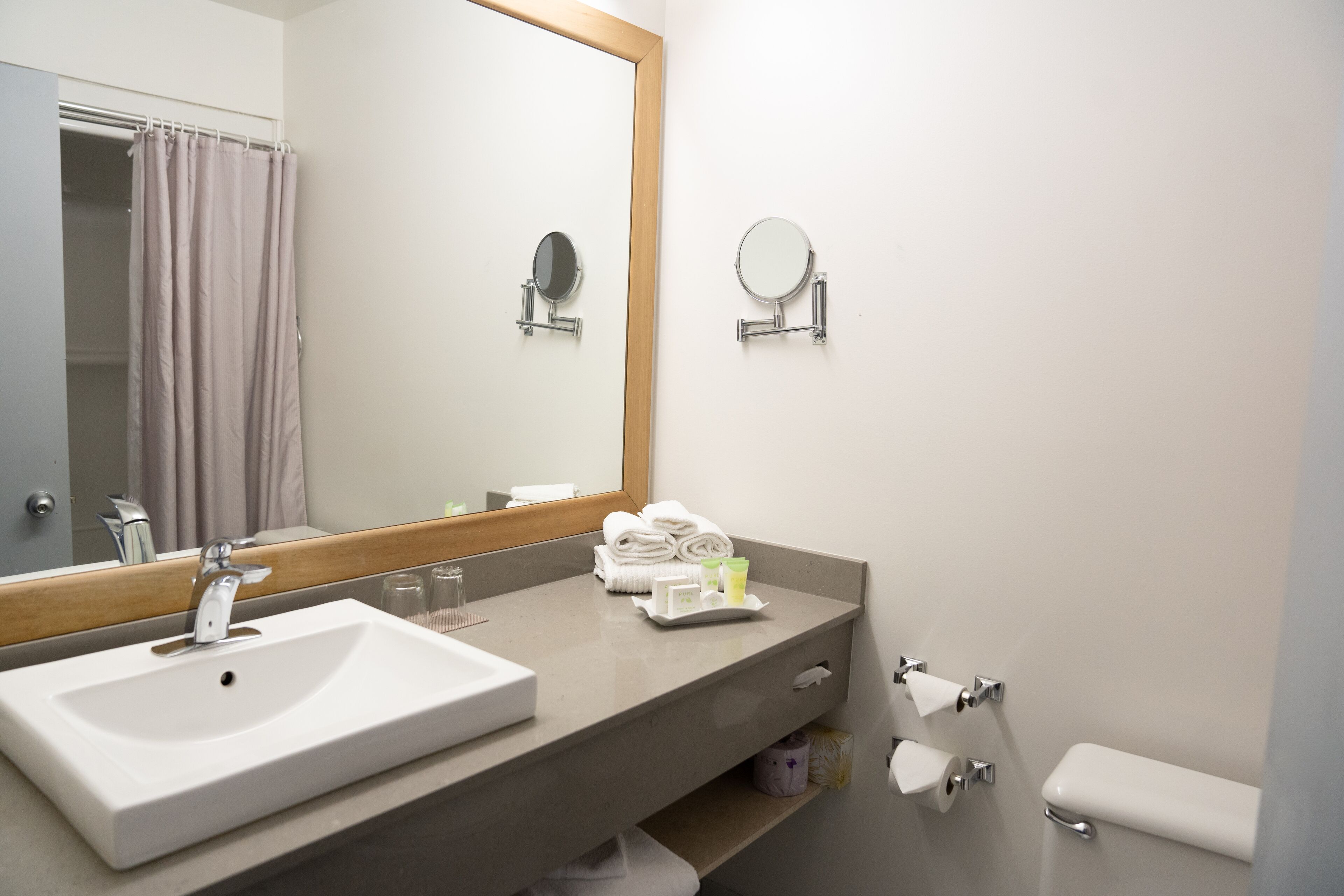 Une salle de bain avec un grand miroir, un lavabo, un porte-serviettes et des toilettes.