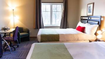A hotel room with a bed, a desk, a chair, and a window with curtains.