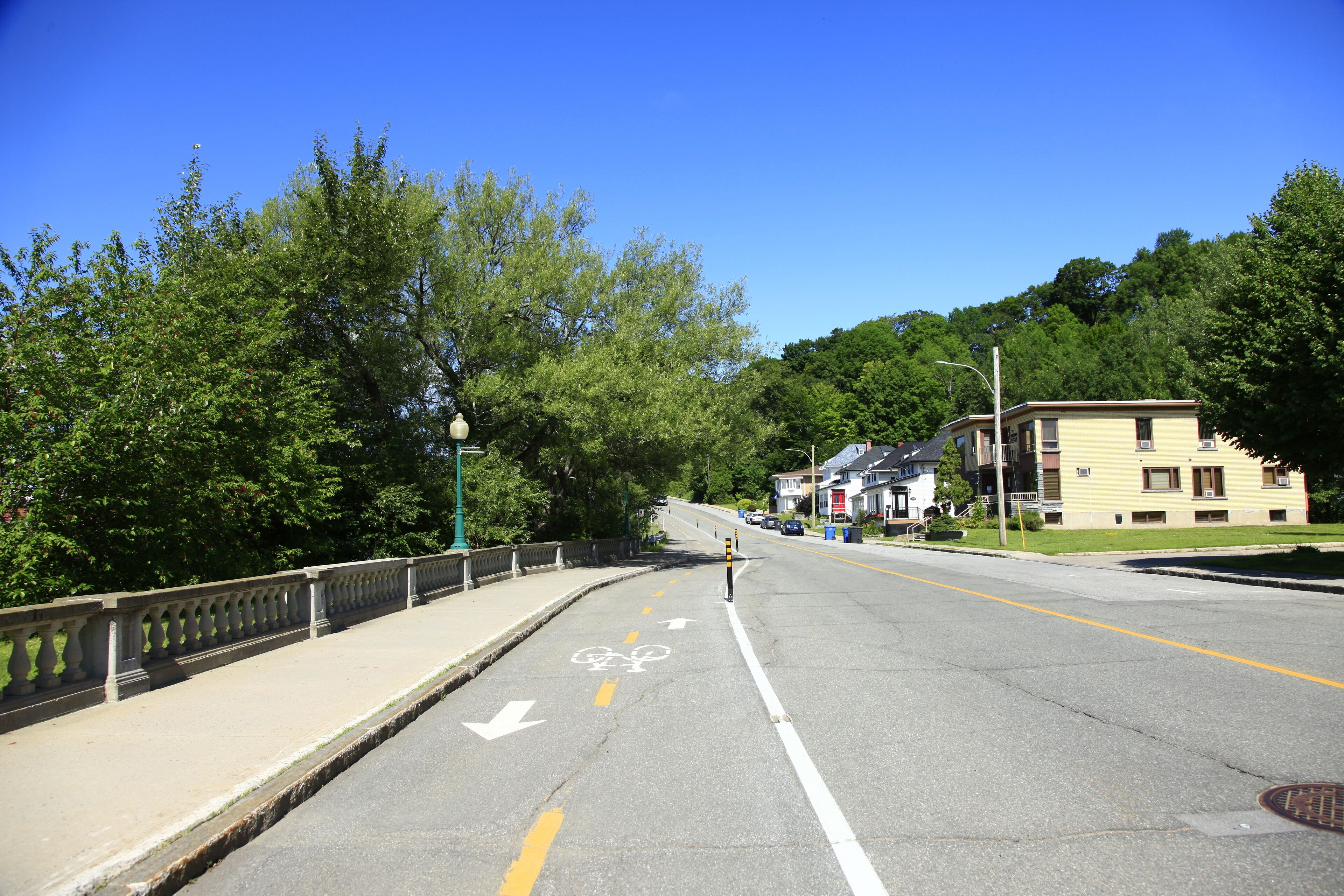 A road with a bike lane, a sidewalk, and a bridge.