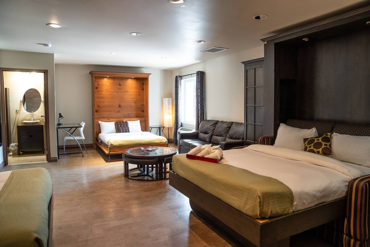 Une chambre d’hôtel avec un grand lit, un canapé, une petite table et un bureau avec une chaise.
