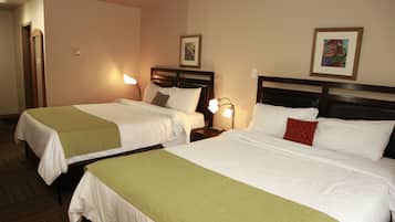 Une chambre d’hôtel avec deux lits, chacun recouvert d’une couvre-lit verte, doté de draps blancs et muni d’une table de chevet avec une lampe.