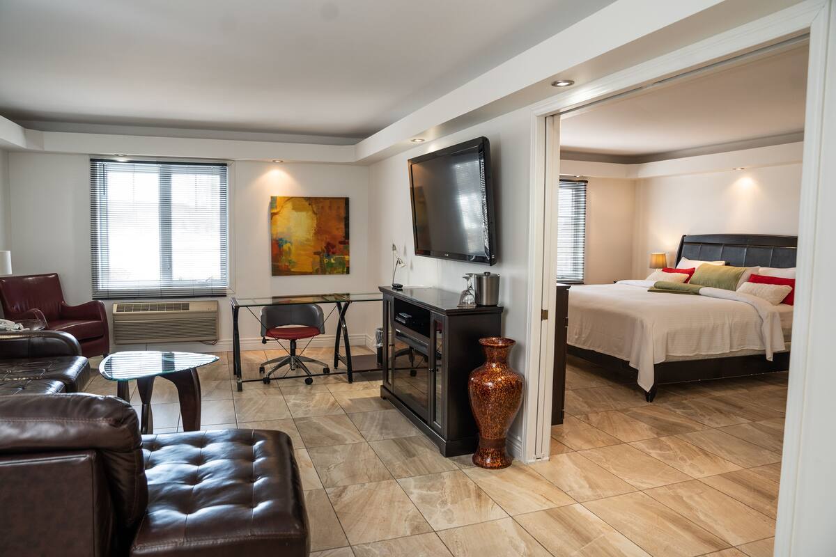 Une chambre d’hôtel moderne équipée d’un lit, d’une télévision, d’un bureau et d’un canapé en cuir.