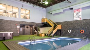 An indoor swimming pool with artificial grass, a hot tub, and a staircase leading to a mezzanine. - Hôtel Énergie Shawinigan (Shawinigan)