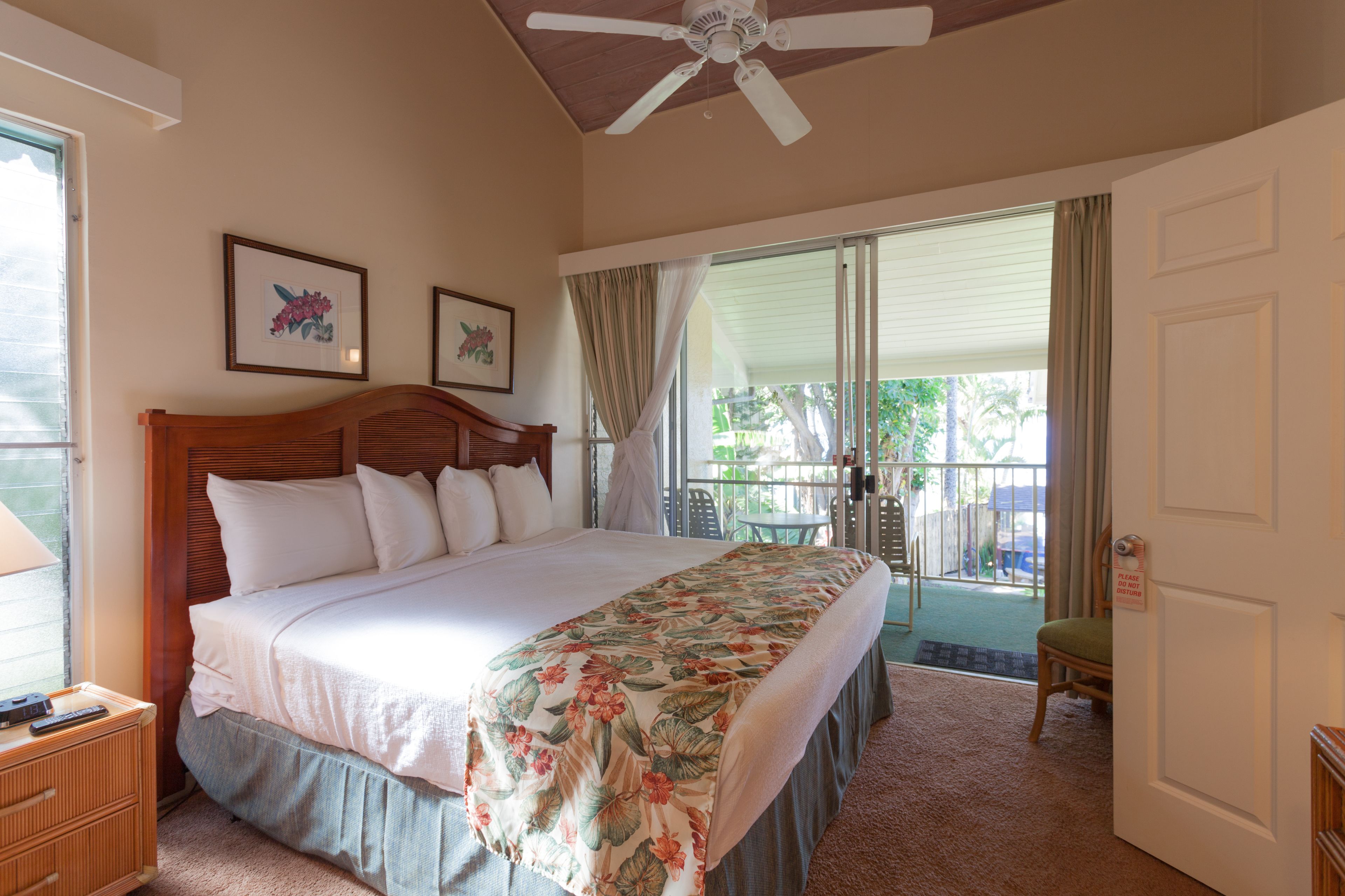 A bedroom with a bed, a ceiling fan, a window, and a door.