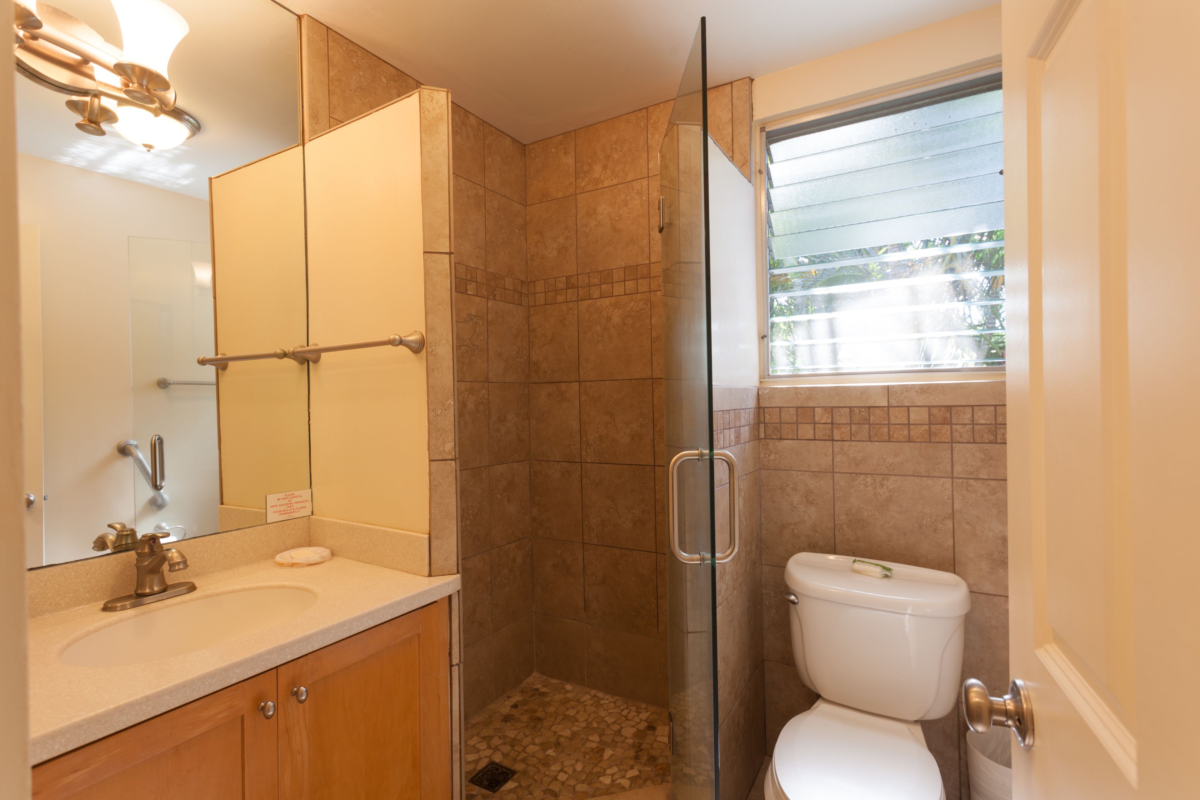A bathroom with a glass-enclosed shower, a sink, and a toilet.