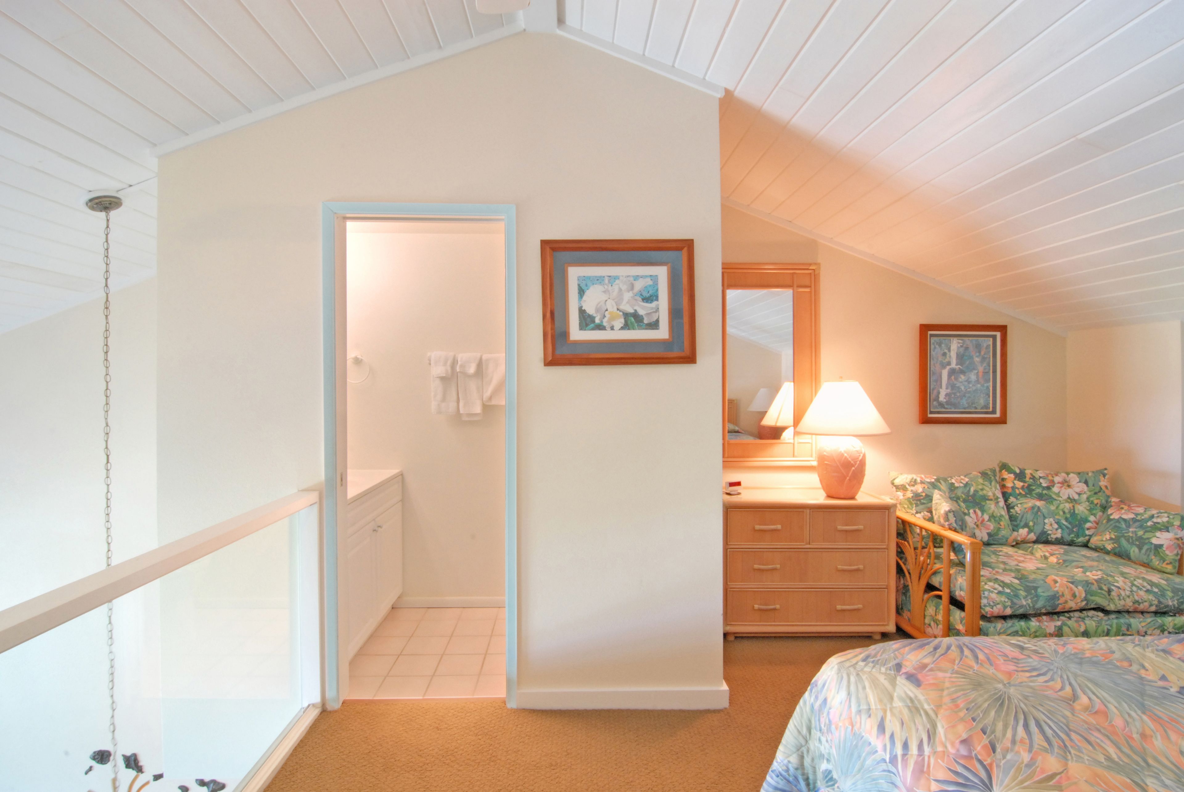 A bedroom with a bed, a dresser, a nightstand, a lamp, and a framed picture on the wall.