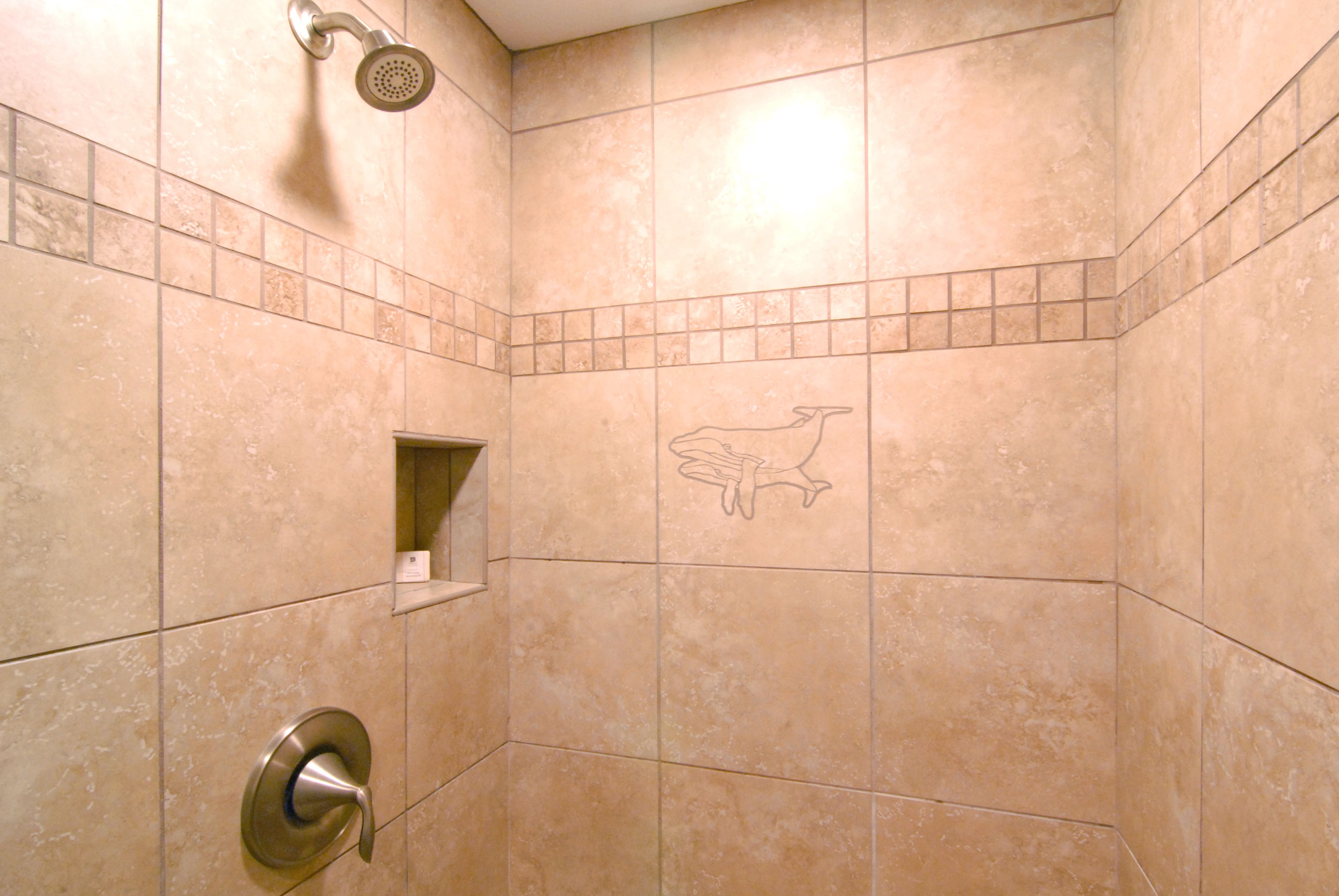 Un baño con baldosas color crema, un cabezal de ducha y un perchero.