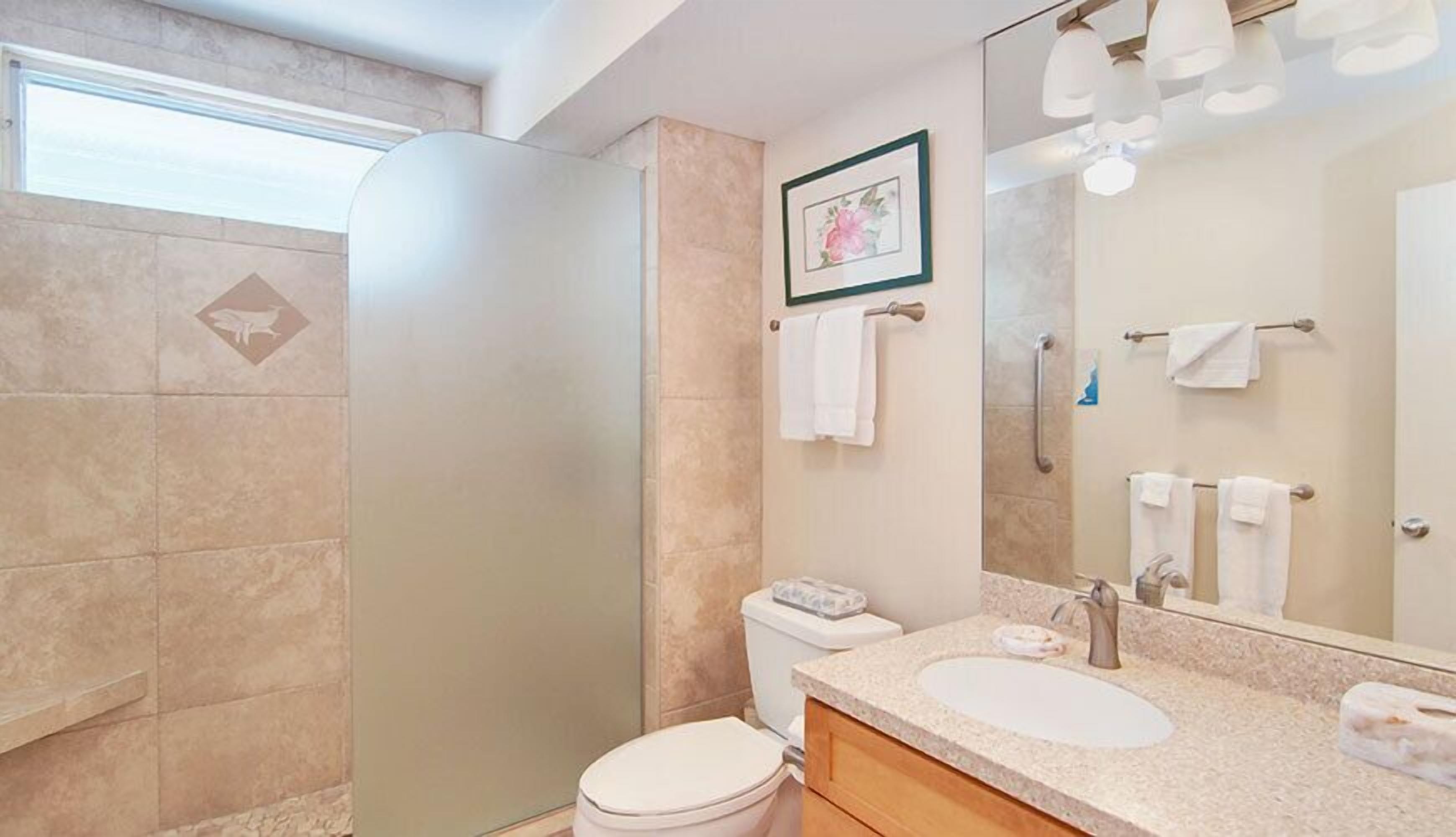 A modern bathroom with a shower, toilet, sink, and a large mirror.