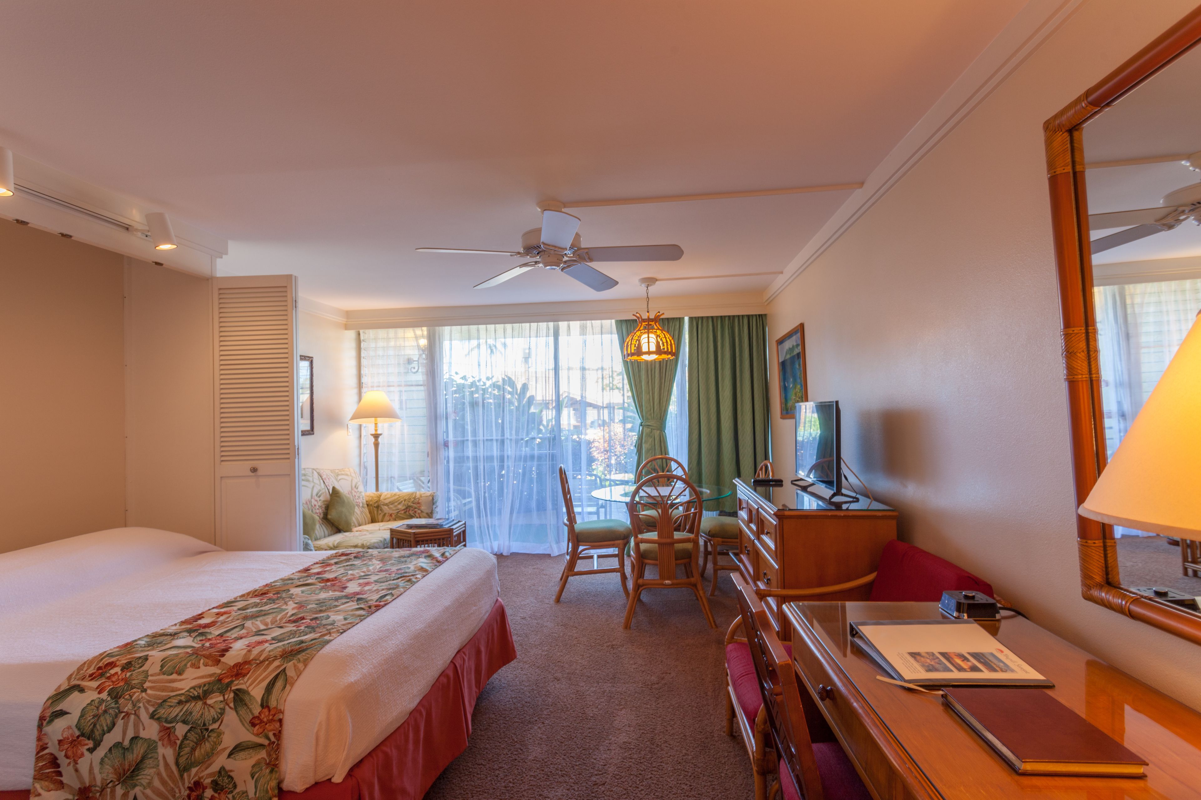 A hotel room with a bed, a desk, a chair, a television, and a window with curtains.