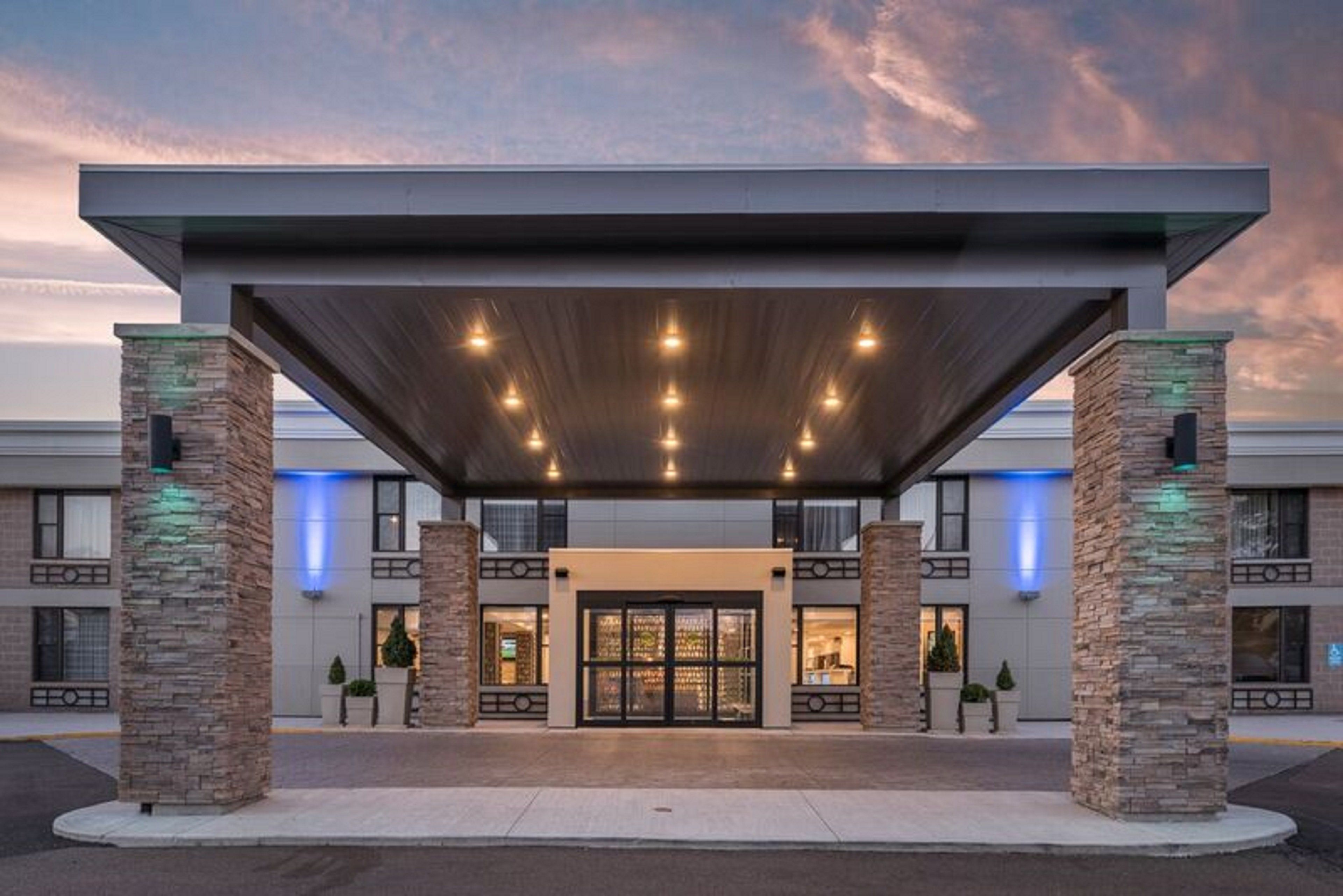 A hotel entrance with a covered walkway, stone pillars, and a glass door entrance.